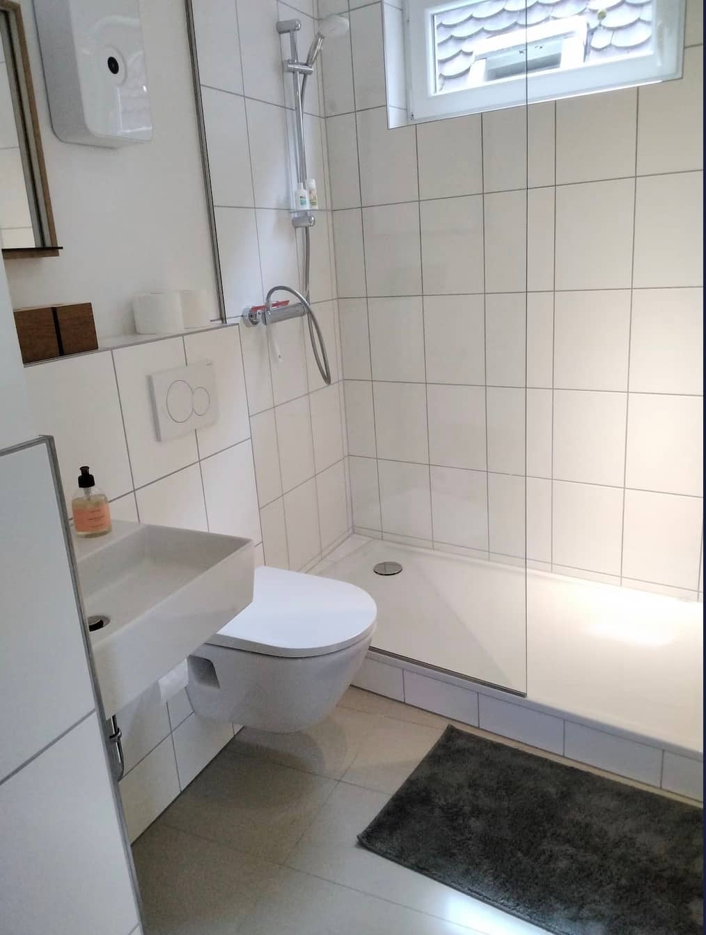 Badezimmer mit bodengleicher Dusche, Waschbecken und Tageslichtfenster