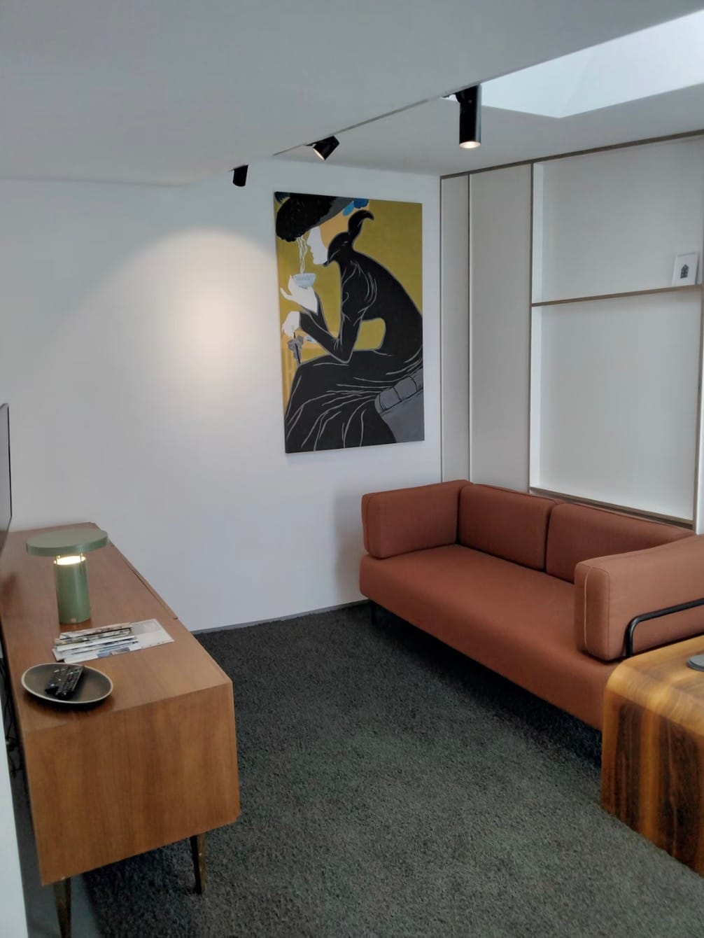 Wohnbereich mit terrakottafarbenem Sofa, Kunstdruck an der Wand und Oberlicht